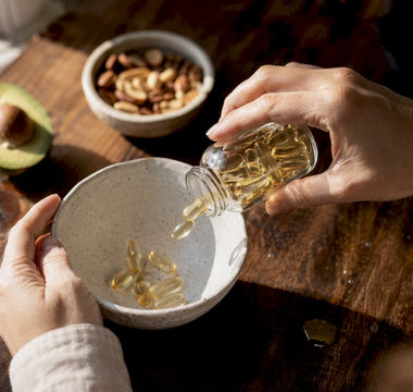 Hænder, der gør klar til at tage D-vitamin med et fedtholdigt måltid