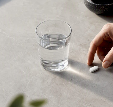 Magnesiumtablet ved siden af et glas vand