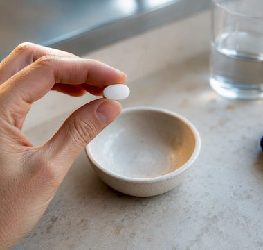 Magnesiumtablet uden mærke sammen med et glas vand