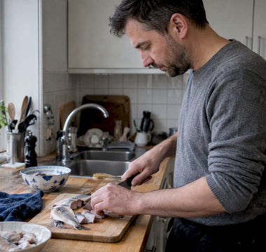 En hjemmekok skærer sild ved køkkenbordet